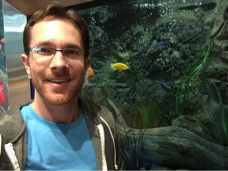 Ben Wehr in front of a large rock-wall cichlid aquarium