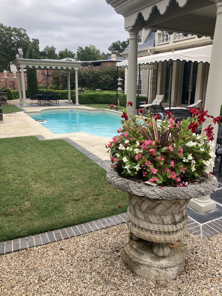 Elegant pool patio with stone urn of colorful flowers